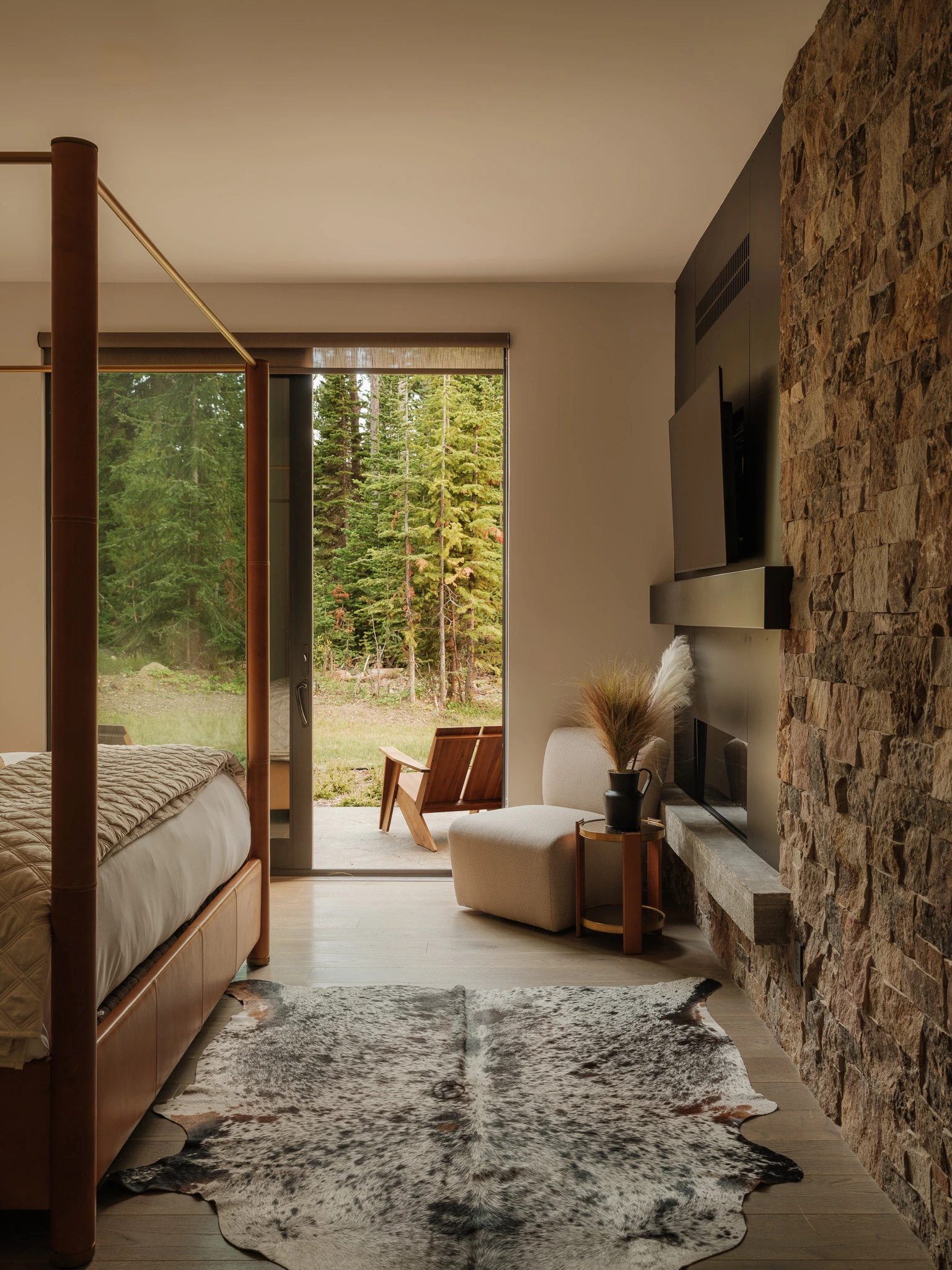Bedroom with stacked-stone wall and sliding door to the meadow — interior design photography Big Sky Montana, Speedwell Cabin
